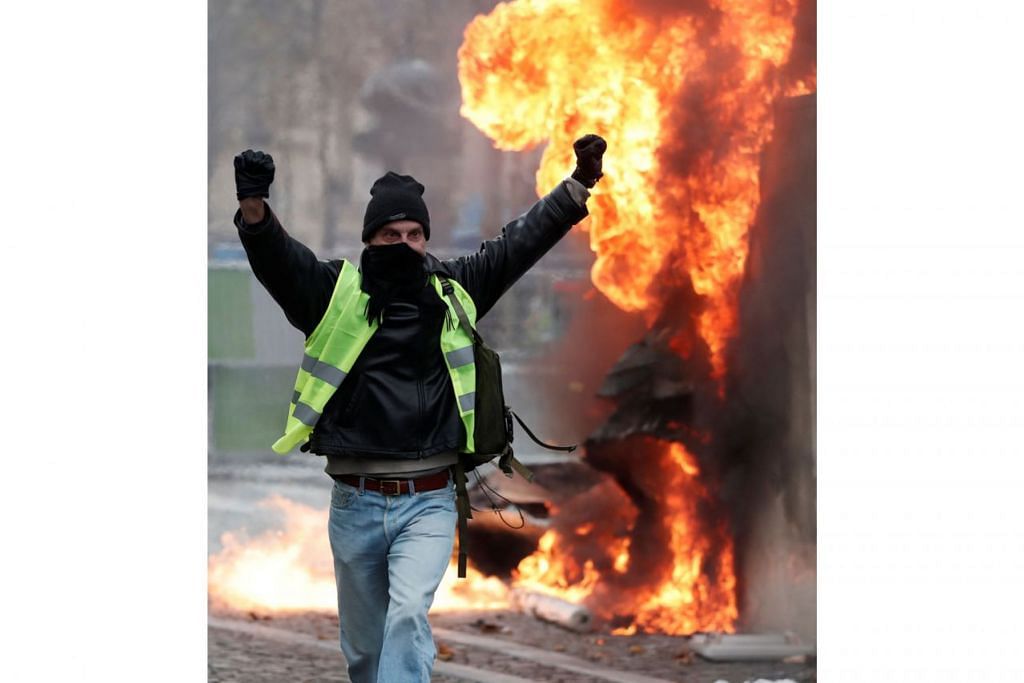 PERBUATAN GANAS: Seorang penunjuk perasaan yang memakai ves kuning, lambang bantahan terhadap cukai bahan bakar yang lebih tinggi, bergerak di hadapan sebuah kereta yang terbakar di Paris. - Foto REUTERS 