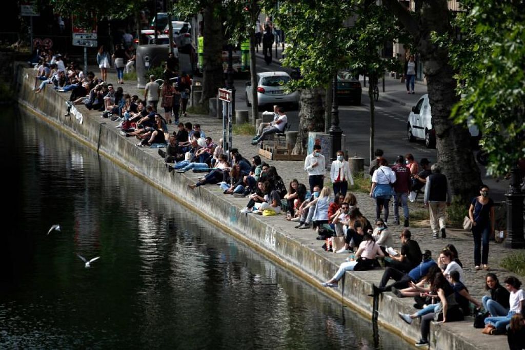 REHAT DAN SANTAI: Orang ramai dilihat meluang masa duduk di pinggir Terusan Saint-Martin di Paris, semalam, setelah pemerintah Perancis melonggarkan sekatan bagi membendung penularan koronavirus.