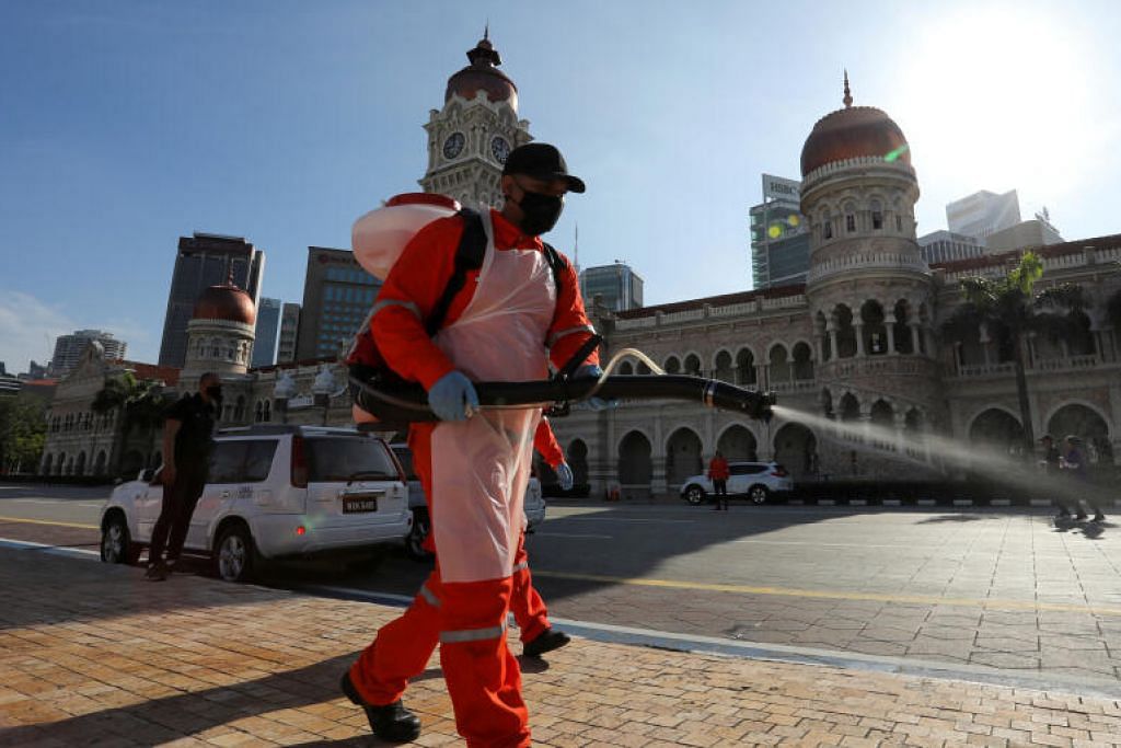 LANGKAH BERJAGA-JAGA: Seorang pekerja di Kuala Lumpur melakukan penyahjangkitan dalam keadaan Malaysia masih lagi bertarung dengan jumlah kes baru koronavirus yang tinggi. - Foto REUTERS