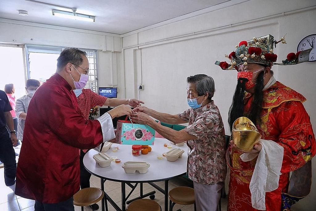 SEBAR KECERIAAN: Dr Tan (kiri) mengunjungi penduduk Marine Terrace dan penerima bantuan GoodLife!, Cik Chan Soh Mui, 87 tahun, sewaktu makan tengah hari sempena Tahun Baru Cina semalam. Dengan mereka ialah lelaki yang berpakaian seperti dewa kekayaan