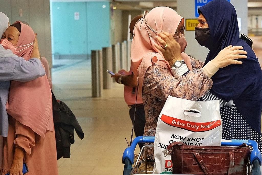 PENUH EMOSI: Jemaah umrah yang dikuarantin di Abu Dhabi, Cik Avathali Azizah (paling kanan), berpelukan dengan Cik Hasnah Abdullah sambil menangis di Lapangan Terbang Changi semalam, mengenang pengalaman yang dilaluinya. Seorang lagi jemaah, Cik Zuha
