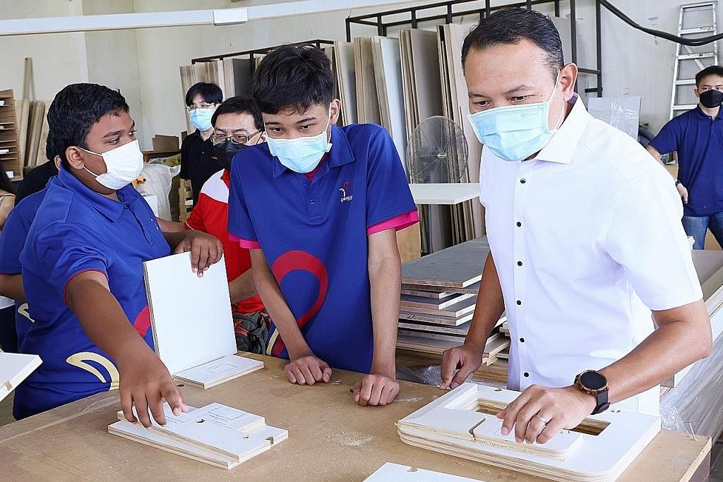 PENDEDAHAN AWAL: Encik Fahmi (kanan) bersama pelajar dari Sekolah Menengah Ping Yi sedang mengambil kepingan kayu setelah rekaan mereka dicetak dari mesin di Threelogy Pte Ltd yang terletak di Tuas. - Foto CDC SOUTH EAST