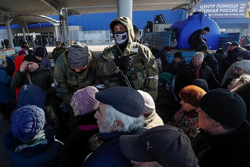 RAKYAT BIASA MENDERITA: Anggota keselamatan yang pro-Russia mengawal keadaan sedang penduduk bandar Mariupol, Ukraine, yang dikepung beratur panjang untuk mendapatkan bekalan bantuan kemanusiaan kelmarin. - Foto REUTERS
