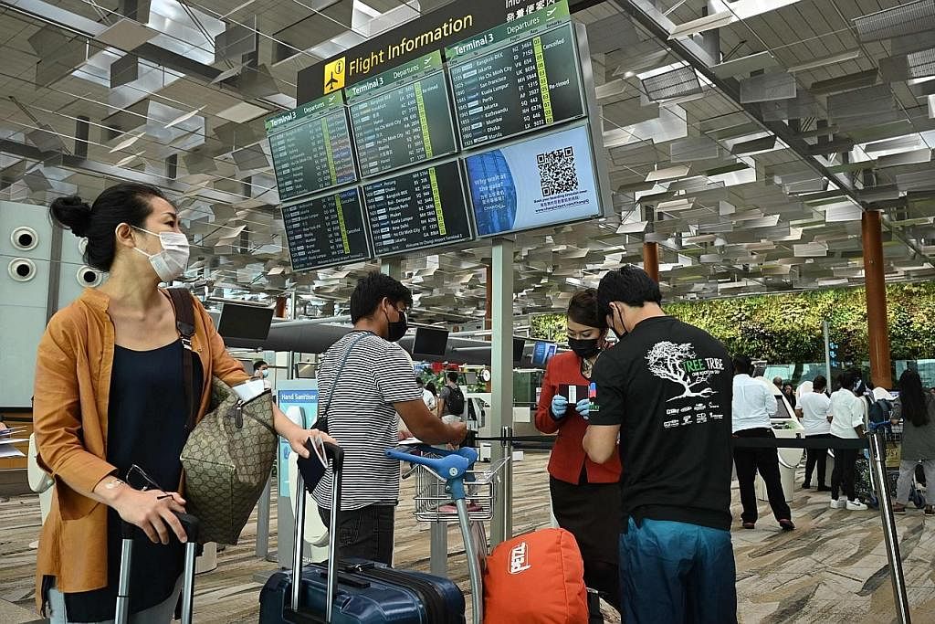 PERIKSA TIKET: Seorang kakitangan di Lapangan Terbang Antarabangsa Changi memeriksa tiket digital penumpang sebelum membenarkan mereka membuat daftar masuk sendiri di dewan berlepas. - Foto-foto AFP SELESAI BERTUGAS: Kru Singapore Airlines tiba di La