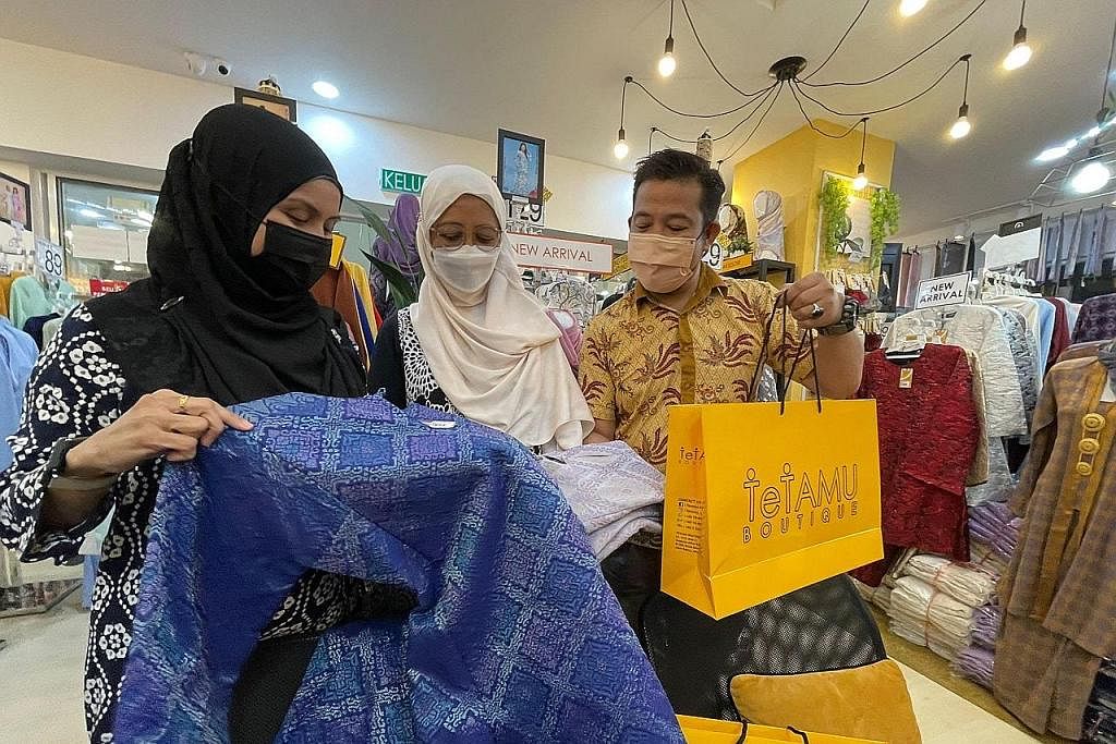 BANYAK PILIHAN: Rakan karib, Cik Tanti Juressa Ong (kiri) dan Cik Azlinah Omari, memilih untuk mendapatkan baju kurung dari butik Tetamu milik Encik Mohd Hairudin Mohd Yasin (kanan).