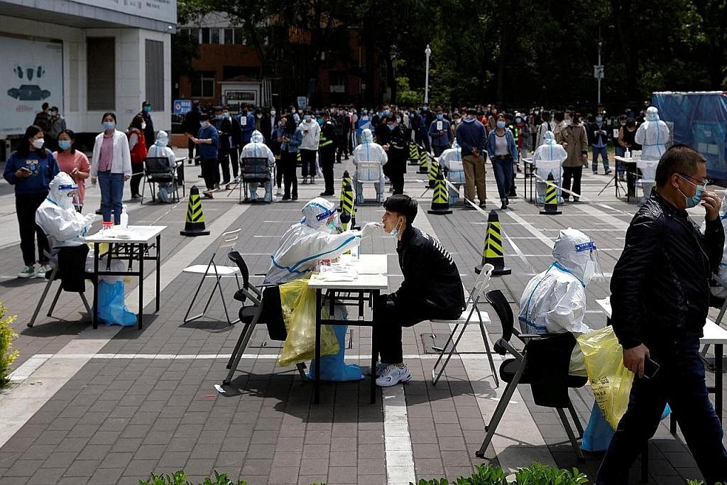 PEMERIKSAAN BESAR-BESARAN: Seorang pekerja perubatan yang memakai alat pelindung diri mengambil sampel colekan daripada seorang penduduk di tapak ujian sementara asid nukleid di tengah-tengah penularan penyakit koronavirus, di Beijing, China. - Foto 