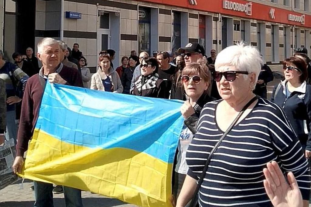 TUNJUK PERASAAN: Beberapa penduduk memaparkan bendera Ukraine semasa mengadakan perhimpunan antipenjajahan di pusat bandar Kherson, Ukraine, kelmarin, yang menyaksikan tentera Russia melepaskan gas pemedih mata dan grenad kejutan. - Foto REUTERS