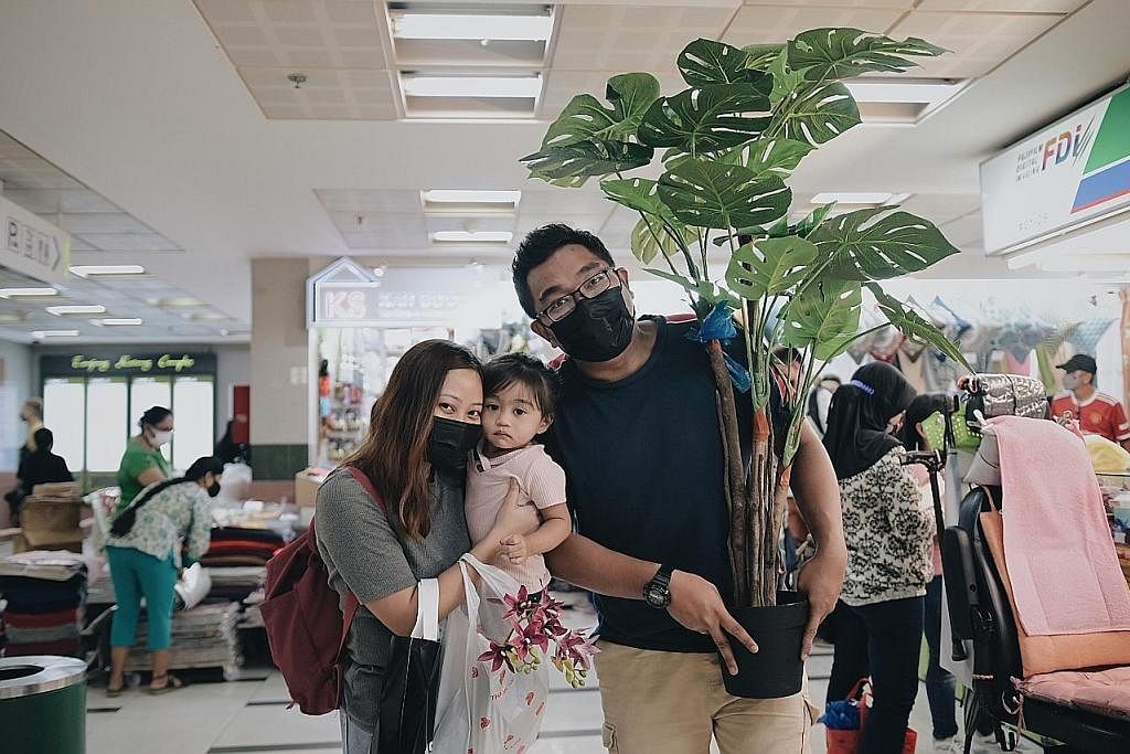 SERONOK BELI-BELAH: Encik Izzwan Suhudi, mengangkat pokok palsu yang baru dibeli di Tanjong Katong Complex semalam dengan isterinya, Cik Tengku Aizura Tuan Abdul Rahim, dan anak mereka, Izzara Adriana, dua tahun.