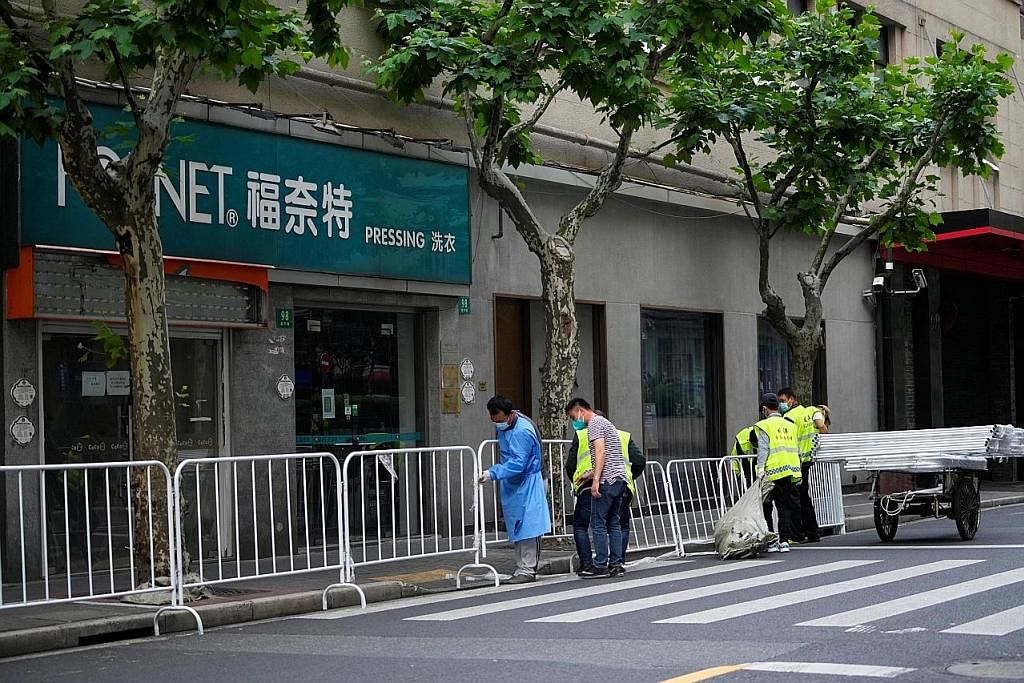 SEKATAN DILONGGAR: Pekerja memeriksa penyekat di Shanghai kelmarin. Penyekat itu dijangka ditiadakan secara bertahap apabila kes Covid-19 terus berkurangan. - Foto REUTERS