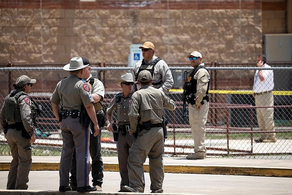KAWAL TEMPAT KEJADIAN: Beberapa pegawai keselamatan dilihat sedang mengawal di tempat kejadian pembunuhan beramai-ramai di sekolah Rendah Robb di Uvalde, Texas, yang membunuh sekurang-kurangnya 21 orang. - Foto REUTERS TERLALU SEDIH: Seorang wanita m