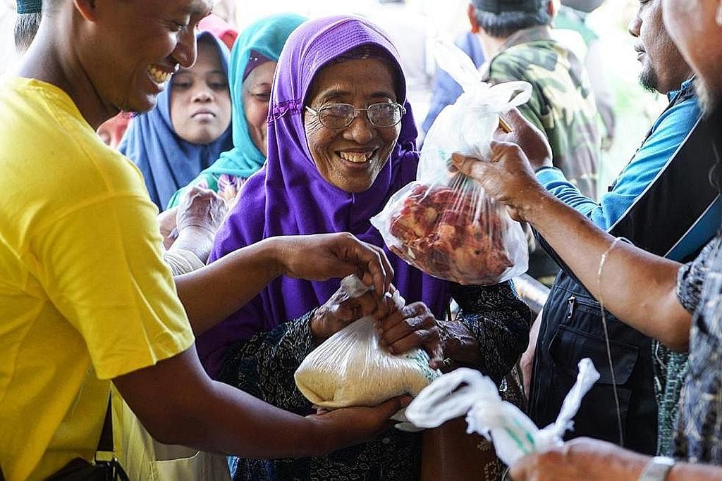 KEBAHAGIAAN TERPANCAR: Seorang penduduk desa dari gunung turun ke stadium Plumbon Pasuruan, Indonesia, untuk menerima sumbangan daging korban dan beras anjuran IbadahSg. - Foto IBADAHSG PTE LTD