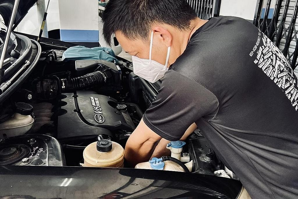 PELANGGAN MULA RAMAI: Encik Adex Chia yang sibuk membaiki salah sebuah kereta milik pemandu SIngapura mula menyaksikan peningkatan perniagaan.