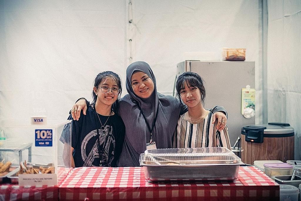 JAGA KEDAI: Pemilik perniagaan Ah Lim Nasi Lemak, Cik Aishah Lim (tengah), anak sulungnya Alisha Lim (kanan), 15 tahun dan Sarah Lim, 14 tahun, mengendali tempahan di gerai mereka di GastroBeats yang berlangsung hingga 26 Jun.