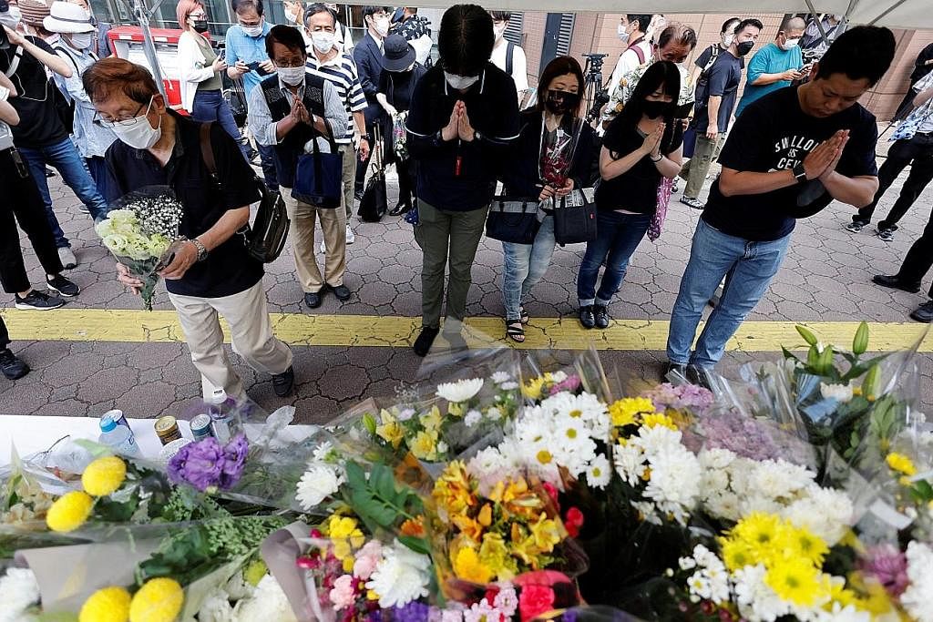 PEMERGIAN MENGEJUT: Orang ramai semalam beratur untuk meletakkan jambangan bunga dan berdoa di tapak mantan Perdana Menteri Shinzo Abe (gambar sisipan) ditembak mati semasa berkempen berdekatan stesen Yamato-Saidaiji di Nara, Jepun. - Foto REUTERS