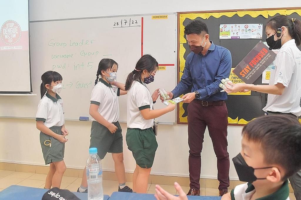 CEGAH DENGGI: Setiausaha Parlimen Kanan (Kemampanan dan Alam Sekitar), Encik Baey Yam Keng (baju biru), mengagih bahan penghalau nyamuk di Sekolah Rendah Pei Tong