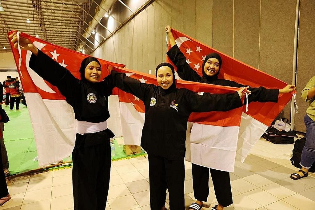 LUAR BIASA: (Dari kiri) Amirah, Ashikin dan Iffah tersenyum lebar selepas dinobat juara bagi acara seni regu puteri dalam Kejohanan Pencak Silat Dunia 2022 di Pusat Dagangan Antarabangsa Melaka malam kelmarin. - Foto SIA KIAN TECK/PERSISI