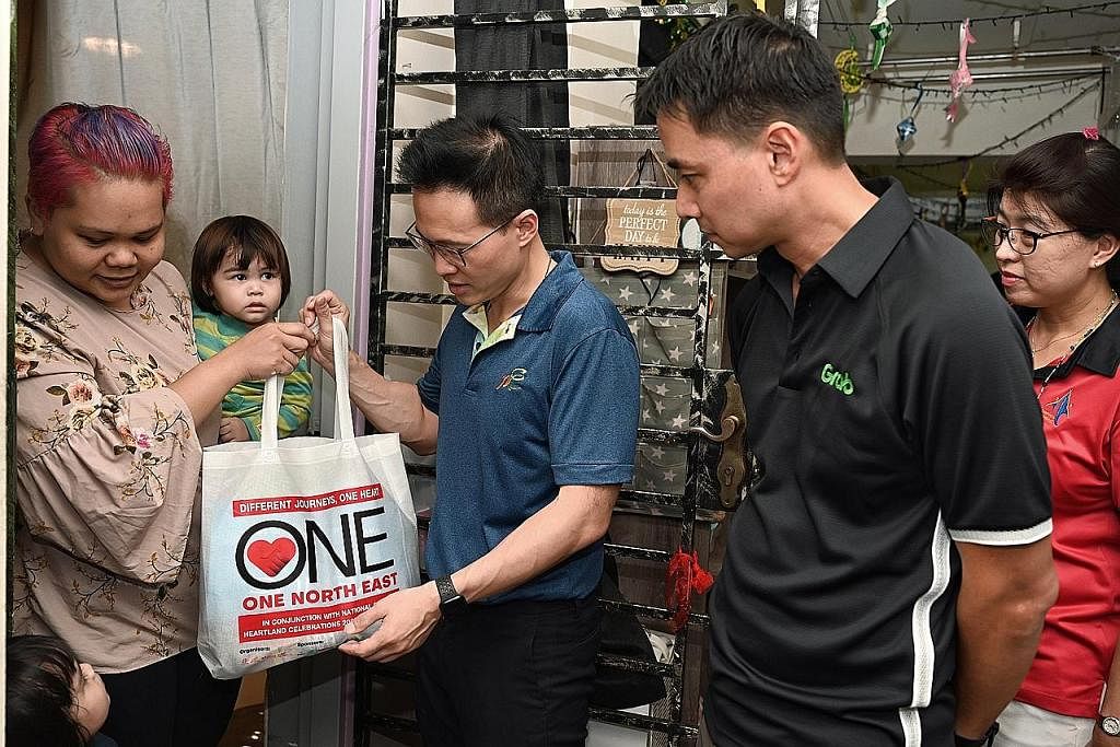 TERIMA HABUAN: Cik Dalia Mansor (mendukung anak) menerima beg yang diisi makanan dan keperluan rumah dari Mayor CDC North East Encik Desmond Choo (tengah) dan Pengarah Urusan Grab Singapore, Encik Yee wee Tang (dua dari kanan). - Foto BH oleh MOHD KH