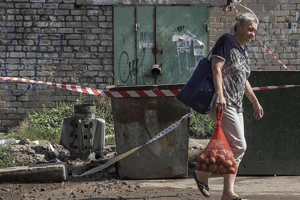 KESAN SERANGAN: Seorang wanita setempat jalan melintasi serpihan roket selepas serangan di bandar Mykolaiv, Ukraine. - Foto EPA-EFE