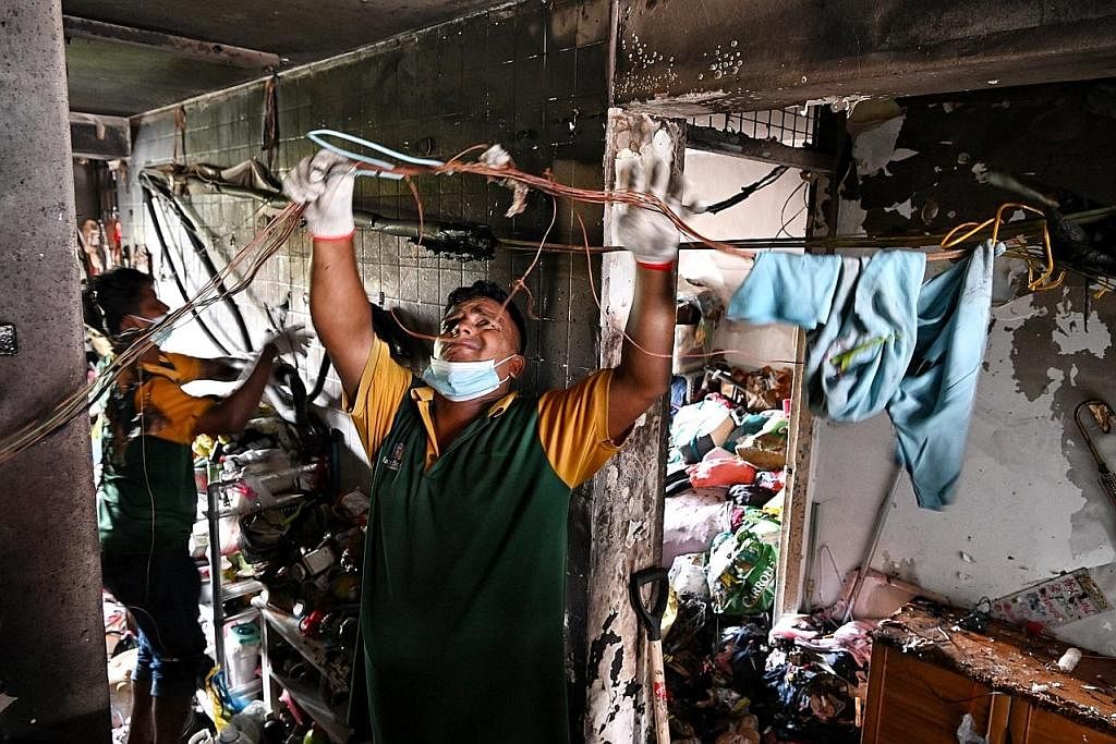 DIJILAT API: Pekerja membersihkan sebuah flat yang terbakar di Aljunied pagi semalam. - Foto BH oleh KUA CHEE SIONG