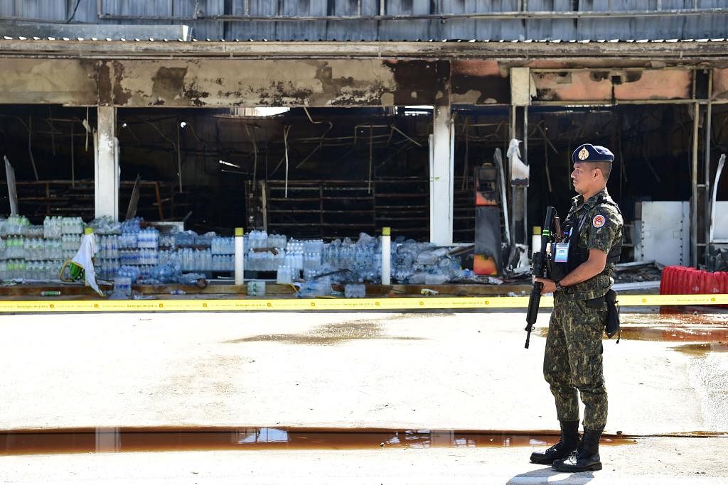 KAWALAN TENTERA: Seorang askar Thailand dilihat mengawal sebuah kedai serbaneka dan stesen minyak yang musnah diserang kaum pemisah di daerah Cho-airong, Narathiwat, selatan Thailand, pada 17 Ogos lalu. – Foto AFP