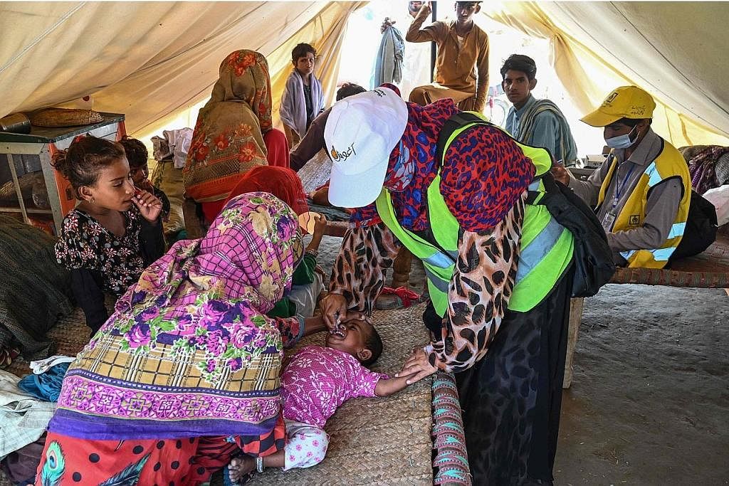 CUBA SELAMATKAN DIRI: Orang ramai yang terjejas akibat banjir kilat berpindah ke kawasan yang lebih tinggi di kawasan Khairpur Nathan Shah, daerah Dadu, wilayah Sindh, Pakistan. - Foto-foto EPA-EFE KESIHATAN DIUTAMAKAN: Pekerja kesihatan memberikan v