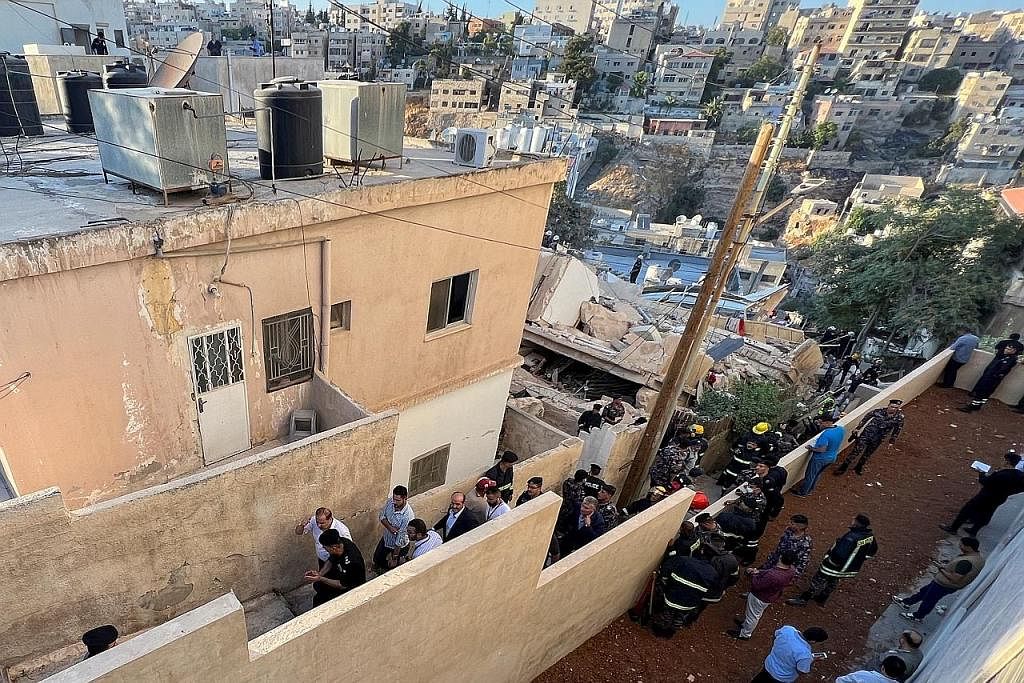 CARI MANGSA: Anggota pasukan pertahanan awam sedang mencari mangsa yang mungkin masih terperangkap di bawah runtuhan di sebuah bangunan yang runtuh di Amman, Jordan. - Foto REUTERS