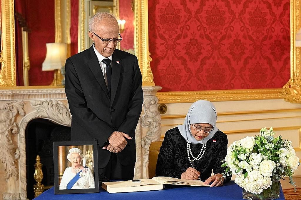 UCAP TAKZIAH: Presiden Halimah, diiringi suaminya, Encik Mohamed Abdullah Alhabshee, menandatangani buku takziah di Lancaster House semasa lawatannya ke London. - Foto AFP