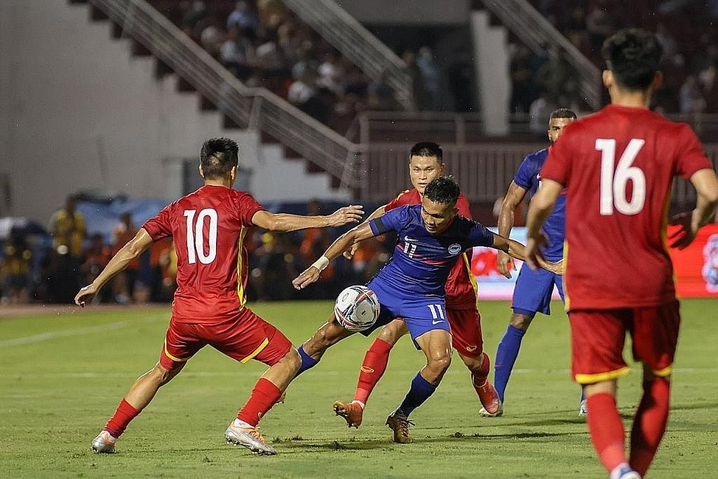 PERLU PERTINGKAT PERMAINAN: Pemain Singapura Hafiz Nor (tengah, jersi biru) cuba melepasi pemain Vietnam dalam perlawanan persahabatan di Stadium Thong Nhat di Ho Chi Minh malam kelmarin. Jurulatih Nishigaya kecewa Singa kalah tetapi berpuas hati aka
