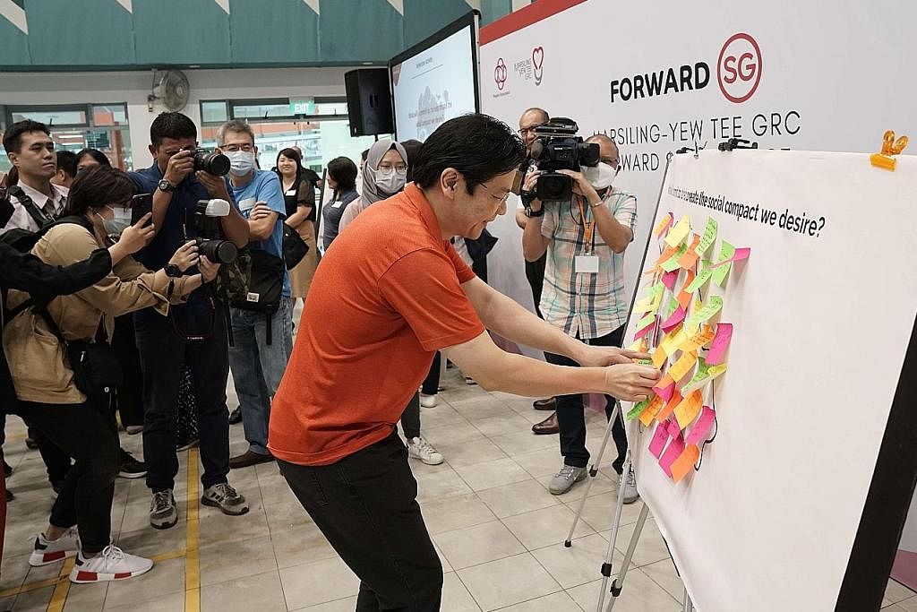 SUARAKAN HALA TUJU: Encik Wong menampal nota 'post-it' di papan tanda yang mengajak para peserta menulis keinginan mereka untuk kompak sosial baru Singapura. - Foto GRC MARSILING-YEW TEE