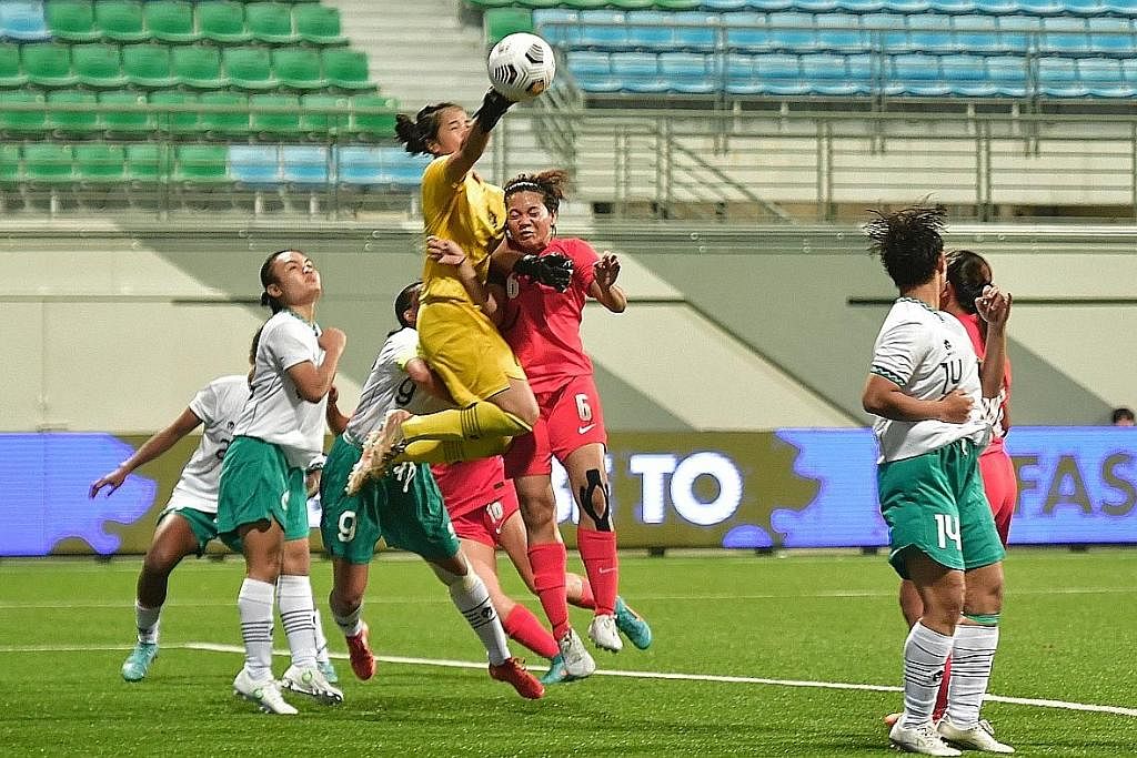 CUBA REBUT BOLA: Pemain Singapura, Nur Farhanah (jersi merah), melompat tinggi untuk cuba menanduk bola semasa menentang Indonesia kelmarin. - Foto BH oleh DESMOND WEE