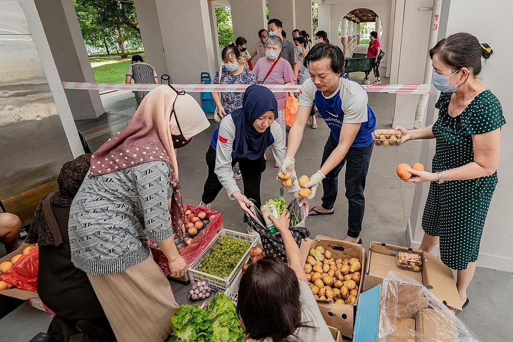 SAYUR UNTUK SEMUA: Cik Azlina Ahmad bertudung biru), dan suaminya, Encik Nurfahmi Sazali, membahagi-bahagikan sayur-sayuran yang masih elok yang 'diselamatkan' dari pasar borong Pasir Panjang kepada mereka yang memerlukan.