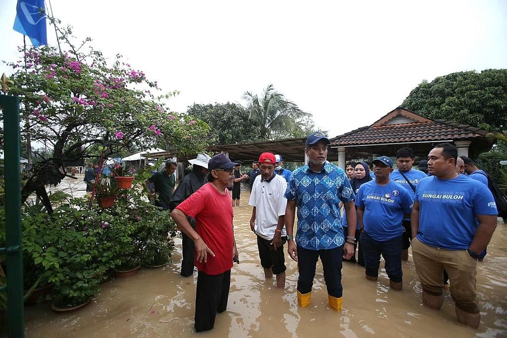 LAWAT KAWASAN BANJIR: Encik Khairy Jamaluddin (berkemeja corak) melawat kawasan di Selangor yang ditenggelami air.