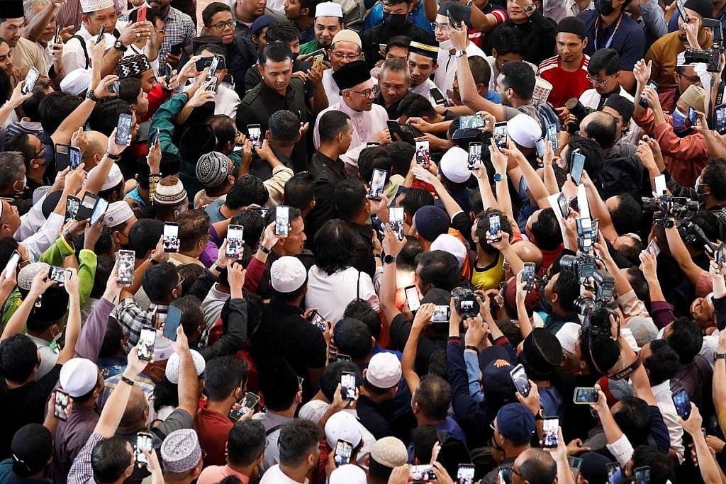 DIKERUMUNI: Datuk Seri Anwar Ibrahim (baju kurung merah jambu) dikerumuni orang ramai setibanya di Masjid Putra sekitar 1.01 petang bagi menunaikan solat Jumaat. - Foto REUTERS