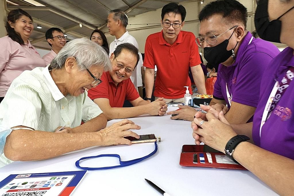 USAHA PENDIGITALAN: Seorang warga emas menunjukkan kemahirannya menggunakan aplikasi e-bayaran kepada Menteri Tenaga Manusia, Dr Tan See Leng (duduk, dua dari kiri), dan Anggota Parlimen (AP) GRC Nee Soon, Encik Derrick Goh (dua dari kanan). - Foto Z