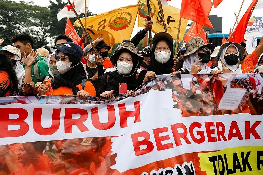 BANTAHAN PEKERJA: Anggota kesatuan sekerja Indonesia (gambar kanan) berkumpul pada Jun 2022 bagi membantah dekri Presiden Jokowi (kiri) yang mengusulkan Undang-Undang Cipta Kerja. - Foto-Foto REUTERS