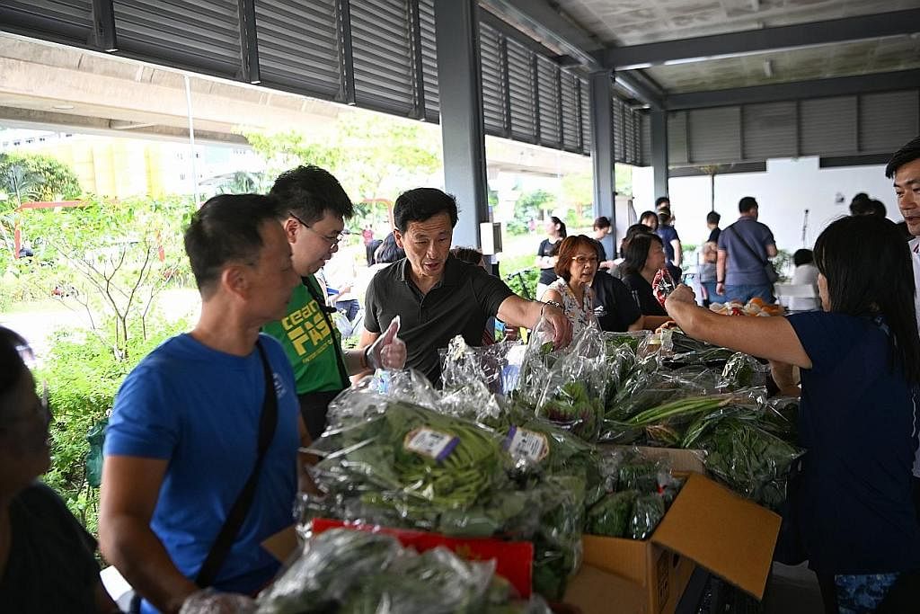 HIDUP LEBIH SIHAT: Encik Ong (tengah, berbaju hitam) bersama relawan mengagihkan sayur-sayuran kepada penduduk yang memerlukan di Pasir Ris Central. - Foto ST