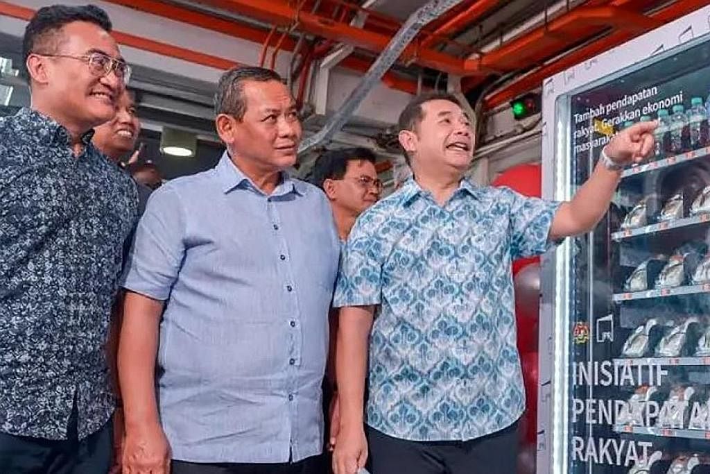 PELUANG NIAGA: Menteri Ekonomi Encik Rafizi Ramli (kanan) bersama Menteri Besar Negeri Sembilan, Datuk Seri Aminuddin Harun (tengah) dan Presiden dan Ketua Pegawai Eksekutif kumpulan, Mohd Azharuddin Mat Sah, melihat sebuah mesin layan diri yang menj