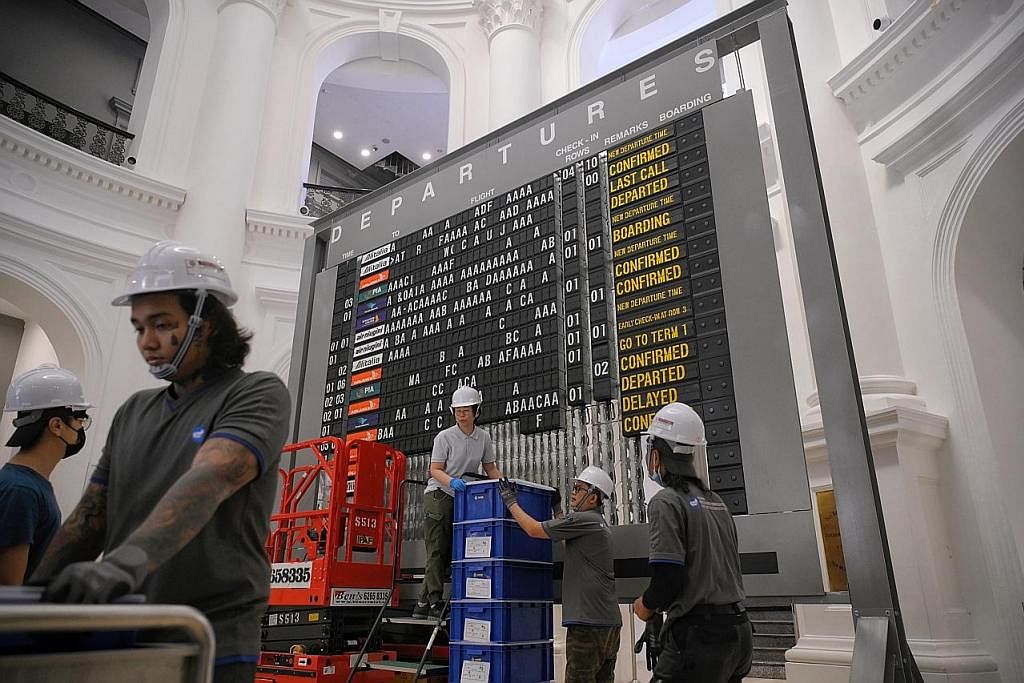 PAPAN IKONIK: Pekerja memasang papan maklumat penerbangan analog di Muzium Negara Singapura menjelang pameran yang meneroka sejarah pelawat ke Singapura dari era 1800-an hingga 2000-an. - Foto ST