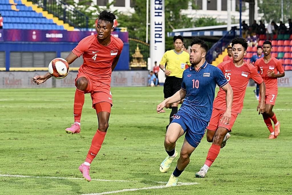 PERTAHANKAN BOLA: Pemain Singapura Bill Mamadou (kiri) menahan bola daripada diasak pemain Thailand. - Foto ST